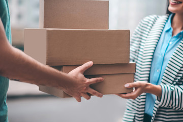 Close up of delivery man passing boxes with order to the customer