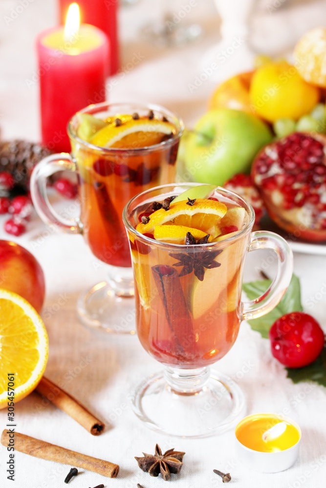 Wall mural hot winter drink Cranberry Apple Cider Punch. Garnish with apples, oranges, and cranberries. hot apple cider with spices on a festive table on Christmas or New Year.