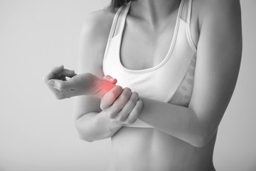 Young woman suffering from pain in wrist on light background, closeup
