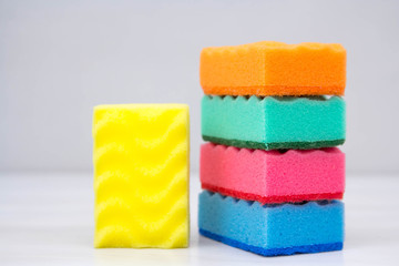 Multicolored sponges for cleaning and washing dishes on a white table. Space for text