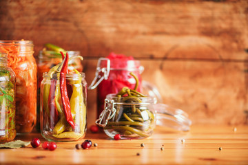 Assortment of various fermented and marinated food over wooden background, copy space. Fermented vegetables, sauerkraut, pepper, garlic, beetroot, korean carrot, cucumber kimchi in glass jars.