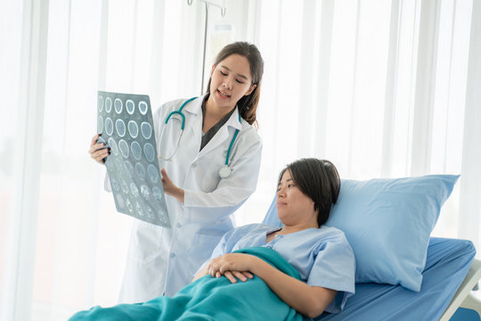 Doctor or physician take care of patient at the hospital.Beautiful female medical doctor is talking to patient reviewing brain X-ray picture,radiographic image,ct scan,mri, isolated hospital clinic.