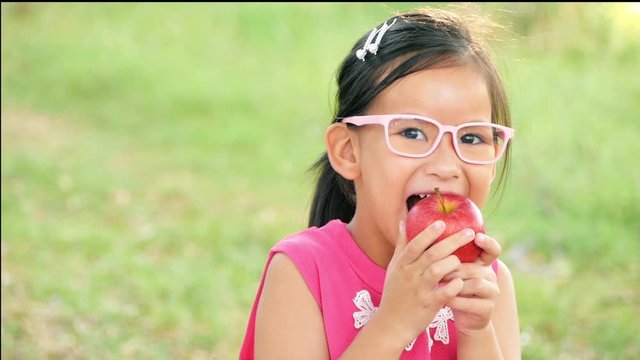 Girl eating an apple in park.
