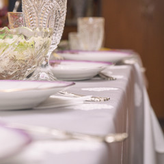 Festive table setting with crystal glasses and plates. Selective focus