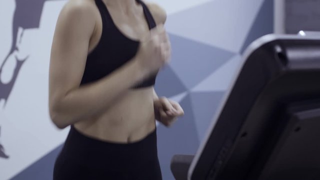 Young sporty woman running on the treadmill at the gym.