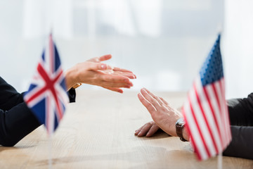 cropped view of diplomats gesturing near flags of america and united kingdom