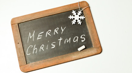 Christmas concept. A white snowflake and a chalk on the old black chalkboard with words Merry Christmas written in white chalk 