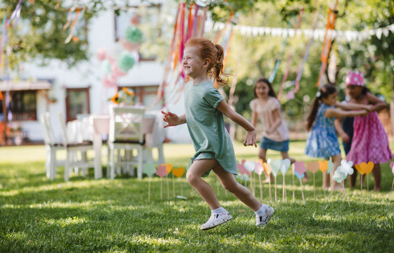 Small children running outdoors in garden in summer, playing.