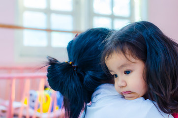 An Asian kindergarten girl is embracing her mother with sadness.