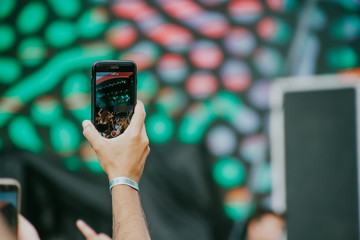 A hand recording a concert with a smartphone