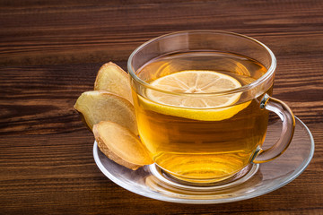 Cup of Ginger tea with lemon and ginger root on a wooden background with copy space