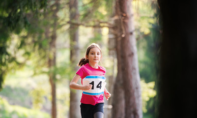 Front view of small child running a race competition in nature.