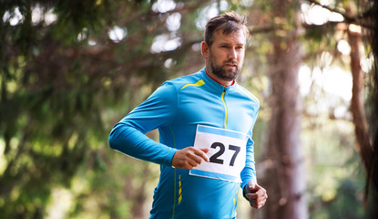 Front view of young man running a race competition in nature.