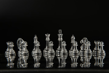 transparent methacrylate chess pieces, front view placed on a reflective black surface