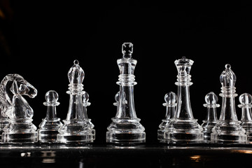 transparent methacrylate chess pieces, front view placed on a reflective black surface