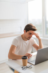 Frustrated with problems young man working on laptop computer at home