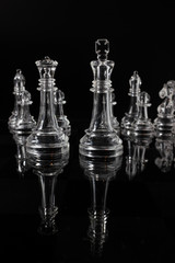 Transparent methacrylate chess pieces, front view placed on a black background. The king and queen as protagonists