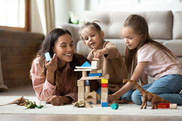 Happy mum with kids daughters playing toys on floor