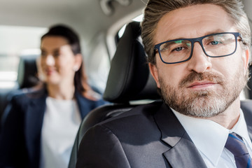 selective focus of handsome ambassador looking at camera near diplomat in car