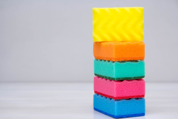 Multicolored sponges for cleaning and washing dishes on a white table. Space for text
