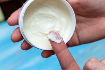 Fototapeta na wymiar applying a white cosmetic cream on the girl hand from jar