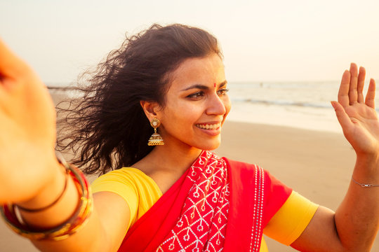 self portrait of gorgeous beautiful indian woman taking selfie photo with mobile phone camera in exotic tropical beach enjoying summer Goa beaches