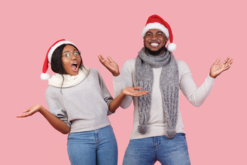 Fototapeta premium Excited Christmas man and woman gesturing over pink background
