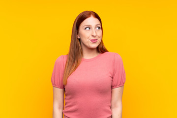 Obraz premium Young redhead woman over isolated yellow background standing and looking to the side