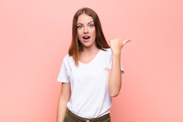 young red head woman looking astonished in disbelief, pointing at object on the side and saying...