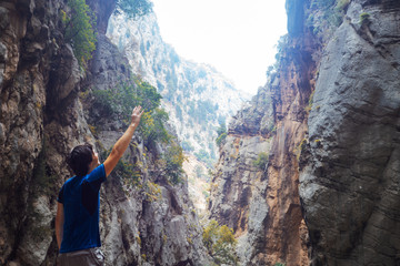 Obraz premium young man climbed a rock, trekking in a gorge. Unity with nature