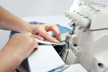 seamstress sews on the overlock. A woman works in a clothing factory.