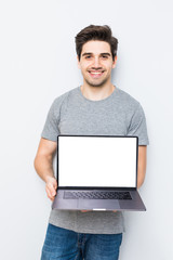 Young man presenting laptop on white screen isolated on white background