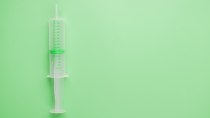 Medical syringe on a green background close-up, copy space. The concept of minimalism.