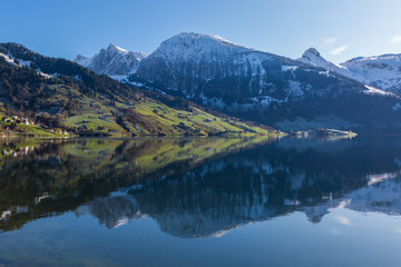 Fototapeta premium snowcapped mountains in blue sky reflected in lake Waeggitalersee