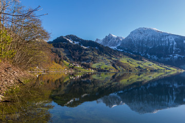 snowcapped mountains reflected in lake Waeggitalersee and blue sky