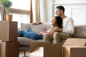 Happy couple dreaming relaxing in own home with boxes