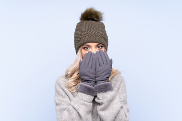 Young teenager girl with winter hat over isolated blue background with surprise facial expression