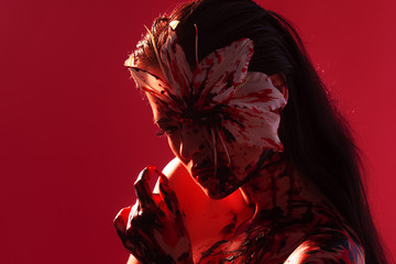 Blood Lily, scary and sexy Halloween image. Beautiful young woman