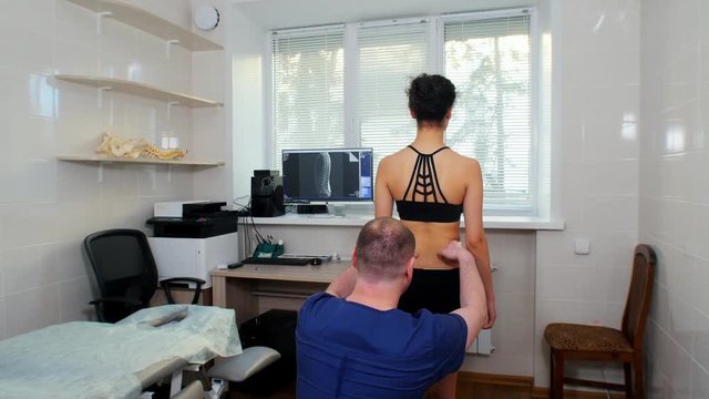 Chiropractic treatment - the doctor inspecting the young woman's lower back