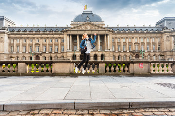 Fototapeta premium Woman jumps up on the background of the Royal Palace in Brussels, Belgium