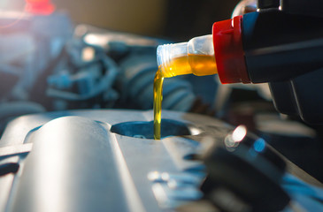 Engine oil change. Fresh engine oil pouring from the canister into the automobile engine. Proper car care background. - obrazy, fototapety, plakaty