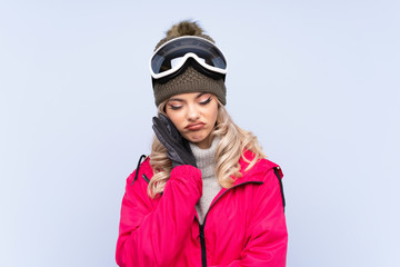 Skier teenager girl with snowboarding glasses over isolated blue background unhappy and frustrated