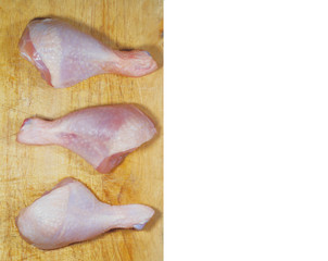 Three raw chicken pieces on a cutting board