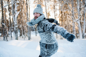Young man having fun in snow outdoors in winter, jumping.
