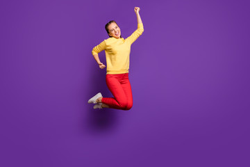Fototapeta na wymiar Full body photo of crazy millennial lady jumping high celebrating champion competition wear casual yellow pullover red trousers isolated purple color background