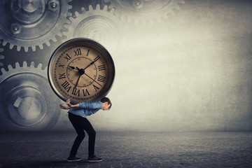 Bent down guy carrying a big heavy clock on his back. Overloaded student tired of daily tasks, and difficult burden. Time pressure and management concept, schedule efficiency, planning and control.