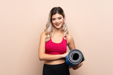 Teenager sport girl over isolated background with a mat and smiling