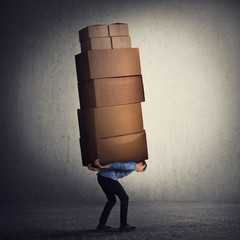 Bent down guy carrying a lot of big heavy boxes on his back. Overloaded of daily tasks, and difficult burden. Packing stuff and moving concept. Mail worker package delivery before christmas holidays. - 305476059