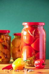 Preserved vegetables in glass jars on green background. Copy space. Healthy fermented food concept. Harvest concept