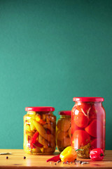 Preserved vegetables in glass jars on green background. Copy space. Healthy fermented food concept. Harvest concept